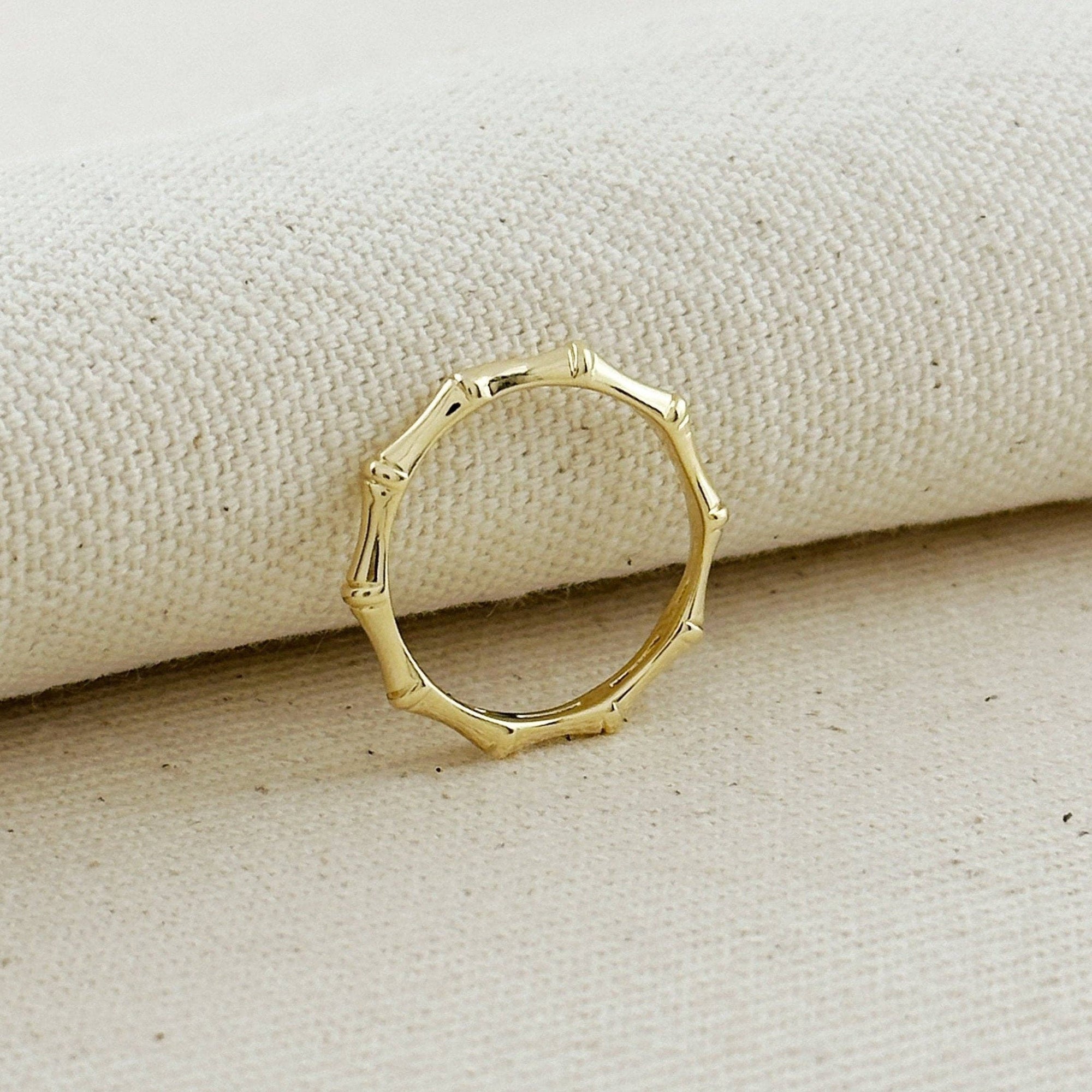Gold ring with a unique design on a beige fabric background