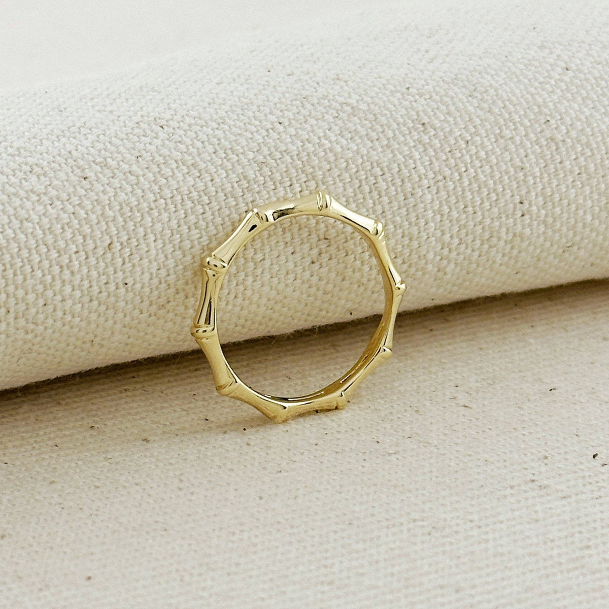 Gold ring with a unique design on a beige fabric background