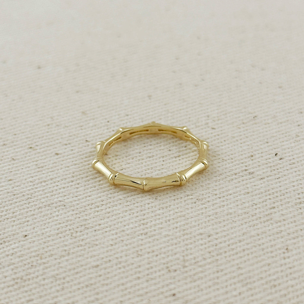 Gold ring with a bamboo design on a beige fabric background