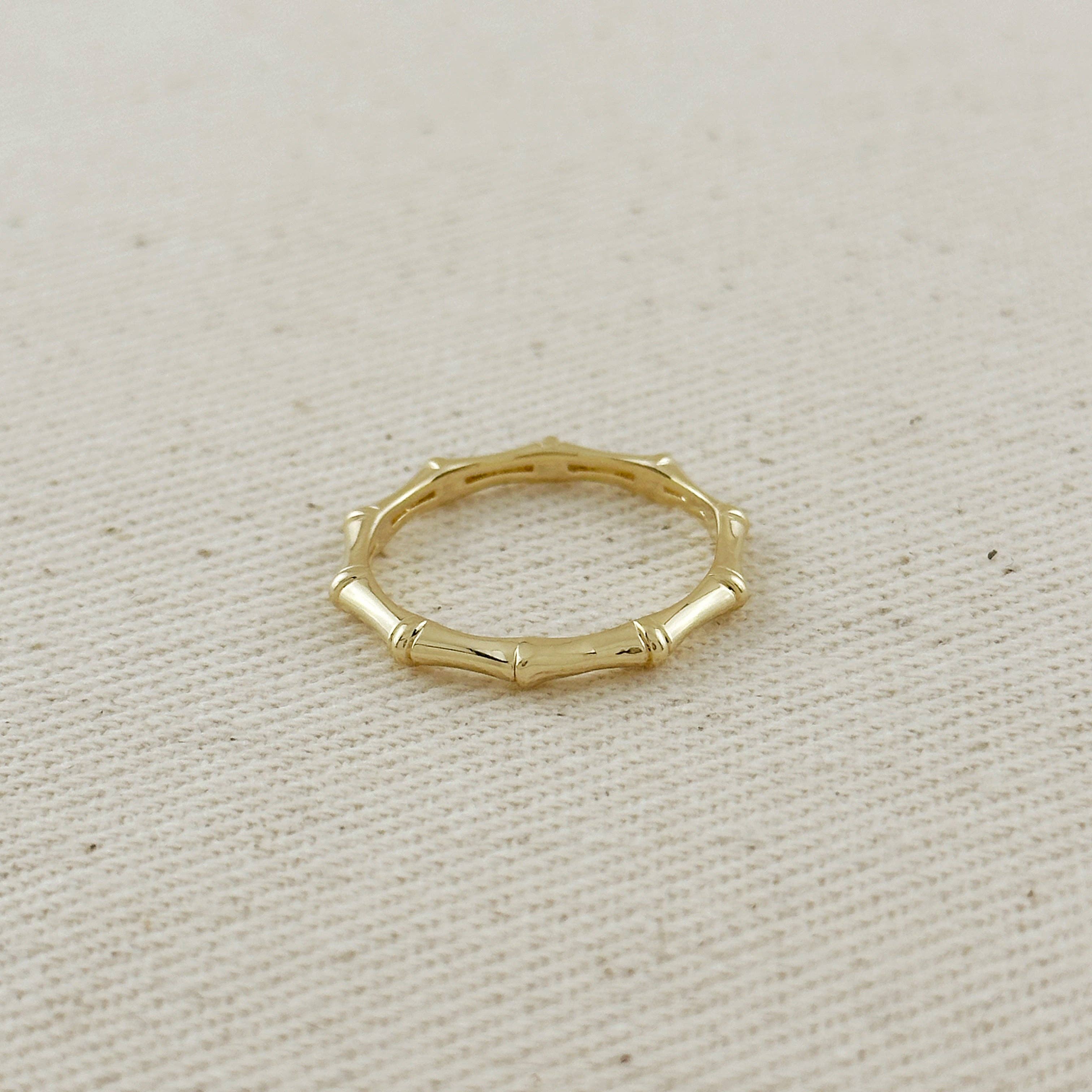 Gold ring with a bamboo design on a beige fabric background