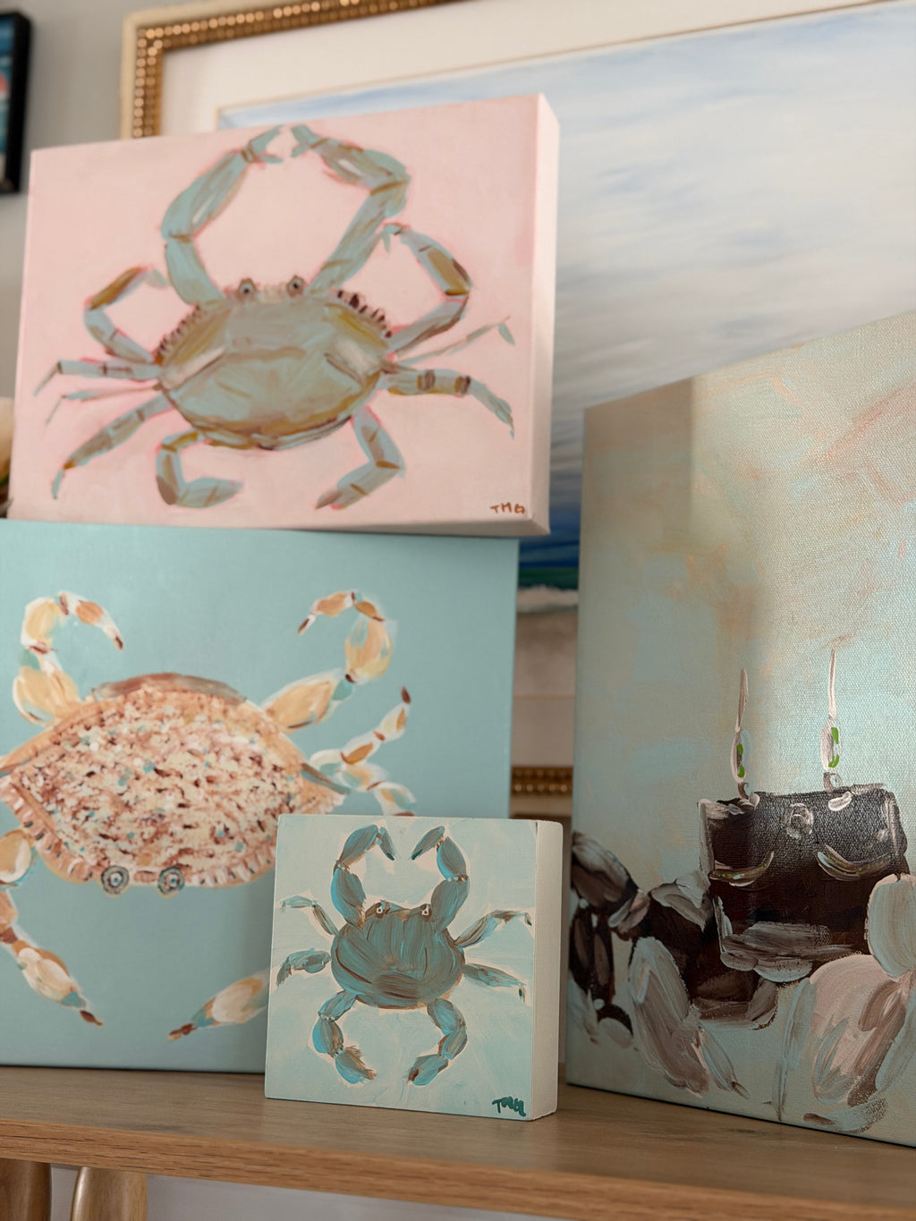 Collection of colorful, hand-painted coastal crab paintings in turquoise, blush pink, and seafoam green by artist Tracy Marie Grogan.
